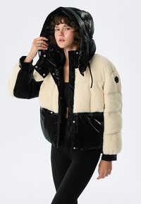 Kurtka puchowa z czarnego błyszczącego nylonu i kremowego sztucznego futra. Zawiera kaptur, napy oraz dopasowany krój z szerokimi rękawami.