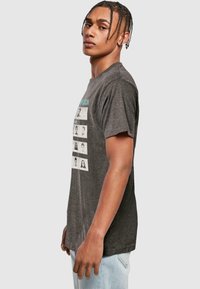 Gray short-sleeve T-shirt featuring a graphic print of faces in black and white, with teal text above, made from soft, breathable fabric.