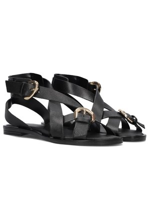 Zwarte leren sandalen met brede kruissluitingen, gouden gespen en een platte zool. Ontworpen voor een open teen pasvorm met enkelondersteuning.