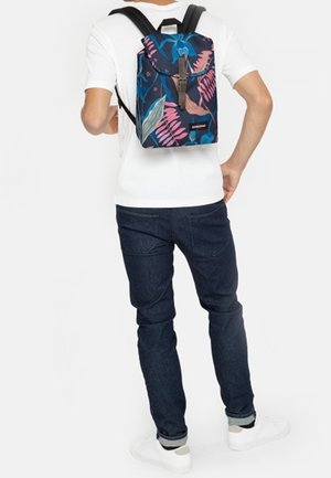 Batoh s květinovým vzorem v modré, růžové a zelené barvě, vyrobený z odolného materiálu, s horním klopou a nastavitelnými popruhy.