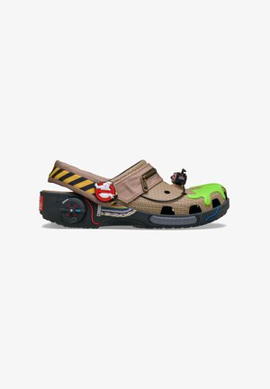 Ghostbusters-themed clog with a black base, green slime detail, and a tan upper. Features a striped strap, decorative hardware, and accents.