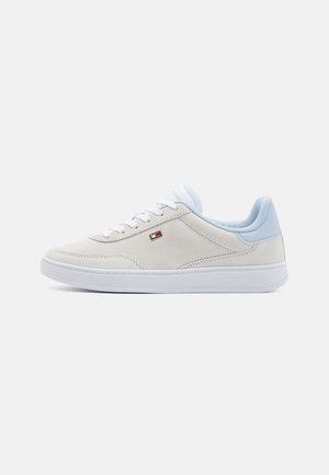 Zapatilla de ante gris claro con cordones blancos y un acento en el talón de color azul claro. Presenta un pequeño logo en el lateral y una suela texturizada.
