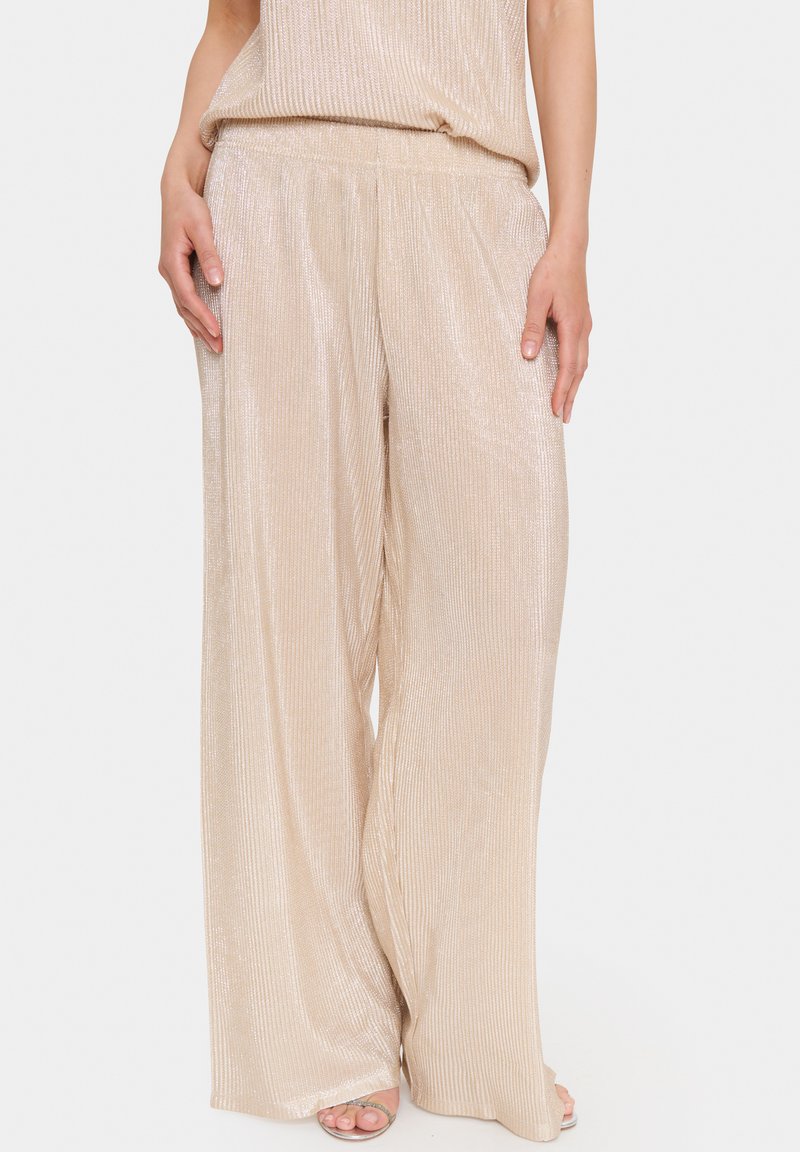 Beige, wide-leg pants with a ribbed texture and subtle shimmer. Elastic waistband and loose fit, enhancing comfort and flow.