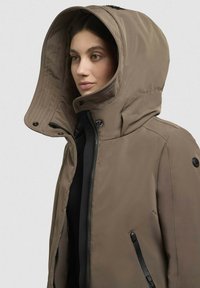 Veste isolée marron avec une grande capuche, fermeture éclair à l'avant et boutons-pression. Présente un design élégant avec des accents noirs et une texture lisse.