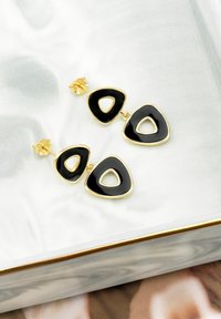 Guldtonade örhängen med lager av triangulära former med en glänsande svart finish. Varje del har urtagna inre trianglar.