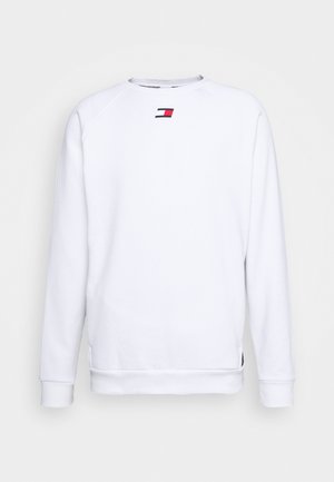 Bílá mikina s dlouhým rukávem a kulatým výstřihem, u krku uprostřed malá červenobíločervená obdélníková značka.