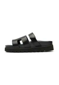 Black slide sandal with two wide straps, cut-out detail, and adjustable Velcro closure. Chunky textured sole for added grip.