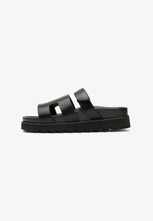 Black slide sandal with two wide straps, cut-out detail, and adjustable Velcro closure. Chunky textured sole for added grip.