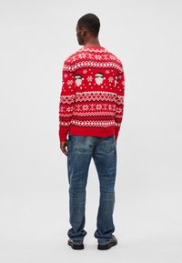 Roter Strickpullover mit Santa-Gesicht-Muster und Schneeflocken, mit Rundhalsausschnitt und gerippten Bündchen, kombiniert mit blauen Jeans.
