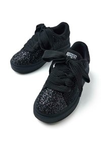 Sneaker nera con upper testurizzato e luccicante, lacci spessi neri e suola ammortizzata. Presenta un logo in evidenza sulla linguetta.