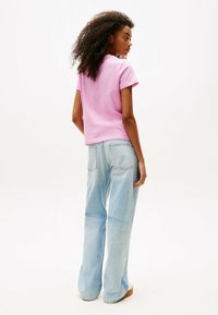 Camiseta rosa de manga corta combinada con unos vaqueros de mezclilla de corte holgado y de color azul claro. La tela parece suave, con un diseño casual y un lavado claro.