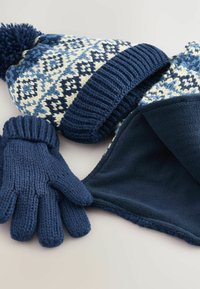 Stickad mössa med pom-pom, prydd med ett blått och krämfärgat Fair Isle-mönster; marinblå handskar; mjuk fleecehalsvärmare i matchande marinblå.