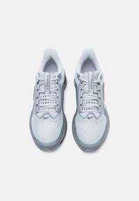 Ανοιχτό γκρι αθλητικά παπούτσια με επάνω μέρος από διχτυωτό υλικό, επενδυμένο κολάρο, υφή στην σόλα και ανακλαστικές λεπτομέρειες. Διαθέτουν λογότυπο και κλείσιμο με κορδόνια.