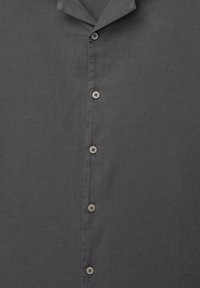 Camisa de botones de tela gris oscuro, con cuello puntiagudo y seis botones claros en la parte delantera. Textura suave, diseño ligero.