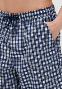 Marineblå og hvite rutete pysjshorts med elastisk midje, justerbar snor og sidelommer. Myk stofftekstur.