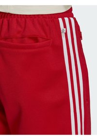 Rode sweatpants met witte verticale strepen, een elastische tailleband en een zijzak. Gemaakt van een soepele, duurzame stof.