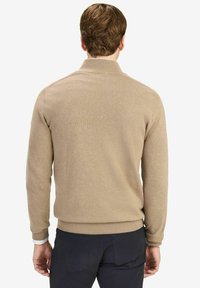 Beige Strickpullover mit hohem Kragen, gerippten Bündchen und Saum. Der Stoff wirkt weich und strukturiert, entworfen für eine figurbetonte Passform.