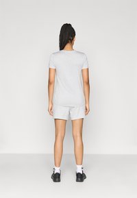 Γκρι κοντομάνικη μπλούζα, σετ με ταιριαστά γκρι σορτς. Λείο βαμβακερό ύφασμα. Απλός σχεδιασμός χωρίς ορατά μοτίβα ή λογότυπα.