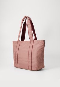 Bolso tote rosa hecho de un tejido suave y duradero, con dos asas resistentes y costuras rojas en contraste para un detalle adicional.