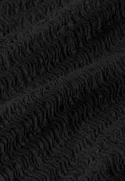 Tessuto nero texture con un motivo ondulato, caratterizzato da una superficie morbida e pelosa. Il materiale appare spesso e potrebbe avere una sensazione accogliente.