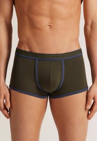 Olivově zelené boxerky s modrým elastickým páskem a lemem. Měkký materiál s přiléhavým střihem, se středním dílem vpředu.