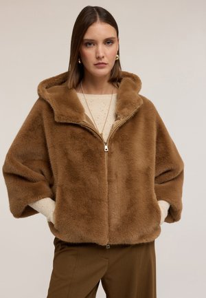 Bruine nepbont hoodie met een ritssluiting aan de voorkant, oversized pasvorm en brede mouwen. Draag over een lichte trui, gecombineerd met een bruine broek.