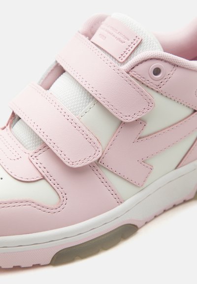 Baskets roses et blanches avec deux larges attaches velcro, semelle texturée et col rembourré, vues en gros plan sous un angle oblique.