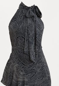 Tamsiai mėlyna suknelė su halter kaklo dizainu ir kaspinėlio detale. Puošia sudėtingi balti paisley raštai ir išplatėjęs apdaila. Minkšta, tekstūruota medžiaga.