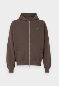 Pruun tõmblukuga kapuutsiga sviiter, millel on ees tasku ja soonikuga varrukad. Vasakul rinnaku kohal on väike tikand.