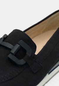 Μαύρο δερμάτινο μοκασίνι με υφασμένο σχέδιο αγκράφας και ανοιχτόχρωμη σόλα. Λείο φινίρισμα με επενδυμένο εσωτερικό για άνεση.