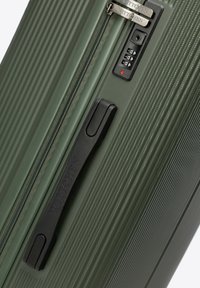 Zelený texturovaný kufr s černou boční rukojetí, zipem a integrovaným kombinovaným zámkem na bílém pozadí.
