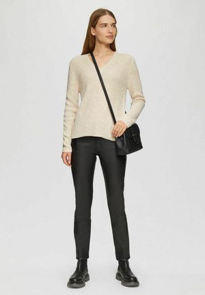 Beige ribbed knit sweater with a V-neck, paired with black slim-fit leather pants and black ankle boots. Black crossbody bag with a clasp.
