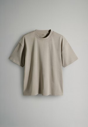 Kurzarm-T-Shirt in hellbeige, aus weichem Baumwollstoff gefertigt. Rundhalsausschnitt mit lockerer Passform und minimalistischem Design. Keine sichtbaren Muster.