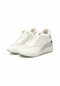 Zapatillas blancas con diseño floral perforado, cierre con cordones, cuello acolchado y tacón gris en cuña. Textura suave con acentos metálicos.