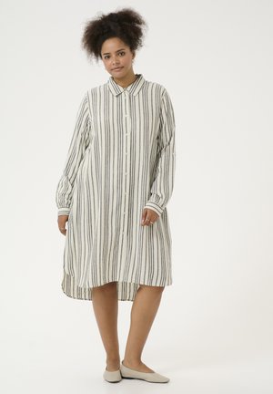 Abito a camicia a righe in crema e grigio, con chiusura a bottoni sul davanti, maniche lunghe con dettagli ai polsini e orlo asimmetrico.