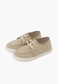 Scarpe in tela beige con suole in gomma bianca, dotate di punta rotonda e cuciture decorative, allacciate con lacci in cotone color crema.