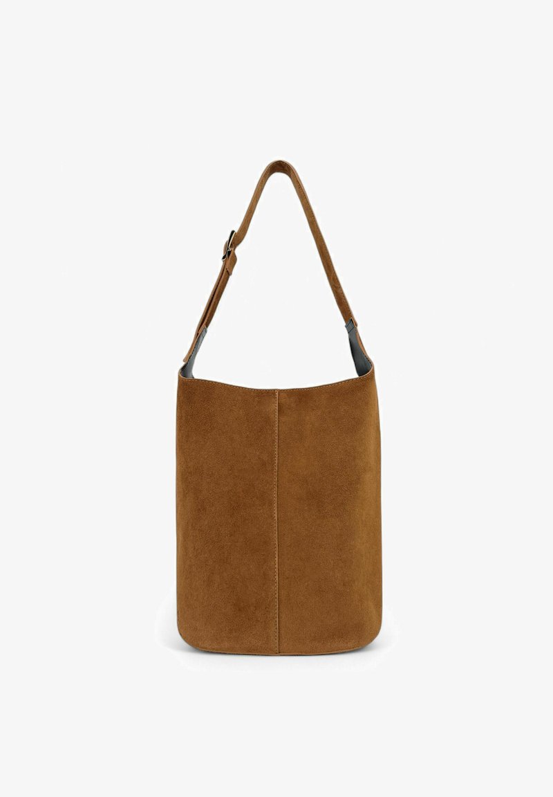 Sac à main en suède marron avec une forme de seau simple, une bandoulière en cuir lisse et des coutures discrètes le long de la couture verticale.