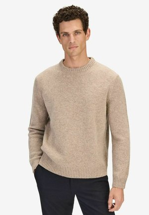 Beige villapusero, jossa on pyöreä pääntie, röyhelöillä varustetut hihansuut ja helma. Tekstuuri näyttää pehmeältä ja lämpimältä, sopii viileämpiin sääolosuhteisiin.
