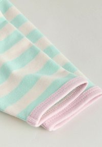 Tissu en coton rayé vert menthe et crème avec un revers rose pâle. Présente une texture douce et un détail de couture subtil le long des bords.