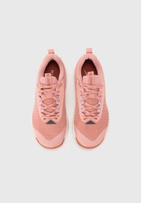 Des chaussures de sport roses avec une tige en maille, une pointe ronde et des lacets texturés. Présente un petit logo noir et des accents dégradés sur la semelle.