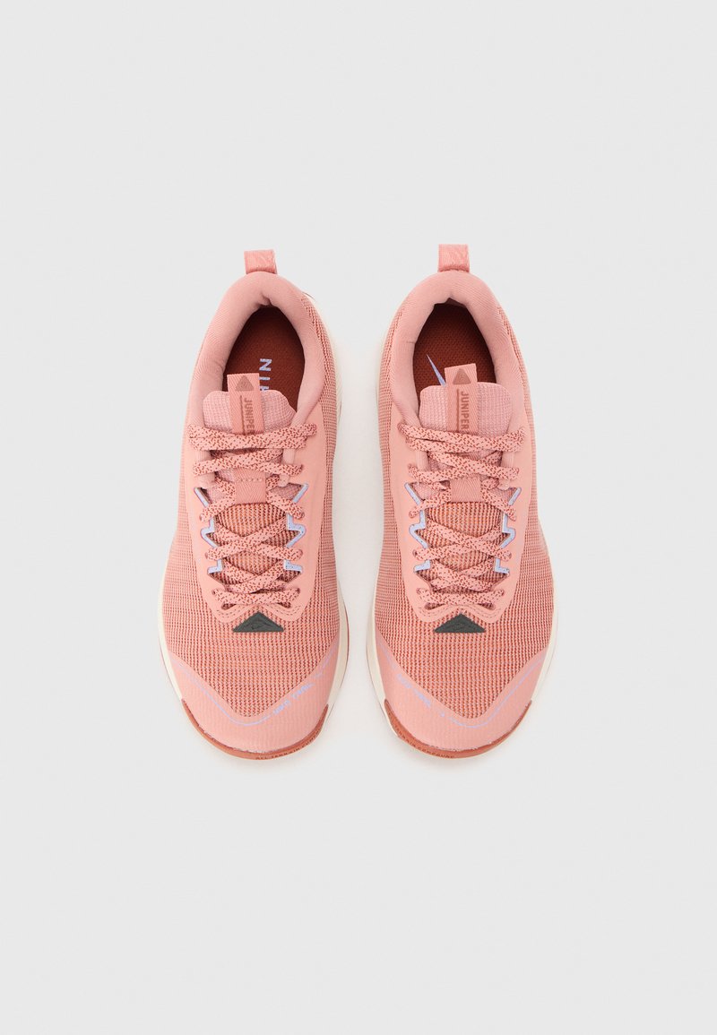 Różowe buty sportowe z siateczkową cholewką, okrągłym noskiem i teksturowanymi sznurowadłami. Zawierają małe czarne logo oraz gradientowe akcenty na podeszwie.