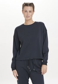 Navyblauw sweatshirt met lange mouwen, ronde hals, ribgebreide manchetten en een trekkoord aan de onderkant. Zacht materiaal met een relaxte pasvorm.