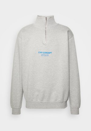 Sudadera gris claro con cremallera de un cuarto, cuello alto, puños y dobladillo acanalados, y texto azul "NY CONCEPT Sports Club New York City" en la parte frontal.