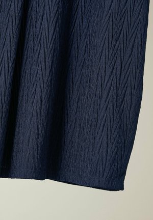 Mørkeblåt struktureret stof med lodrette krøllede mønstre; nederste kant er lige uden udsmykninger eller metaldele.