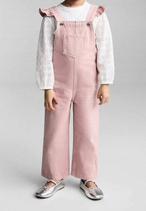 Enfant portant une salopette en velours côtelé rose avec poche avant, un chemisier blanc à manches longues en œillet avec des épaules à volants, et des ballerines argentées.