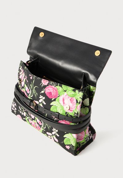 Τσάντα με λουλούδια και μαύρο δερμάτινο καπάκι στην κορυφή. Διαθέτει μαύρη λεπτομέρεια ζώνης, χρυσά μεταλλικά στοιχεία και υφασμάτινο μοτίβο με ροζ/πράσινα λουλούδια.
