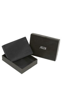 Cartera de cuero negro con diseño minimalista, mostrada parcialmente en una caja oscura. Presenta un logo de la marca en relieve. Textura suave, forma rectangular.