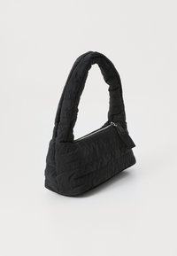 Borsa a tracolla nera trapuntata con una maniglia curva e imbottita e chiusura con zip. Presenta un tessuto testurizzato con lettere in rilievo su un lato.