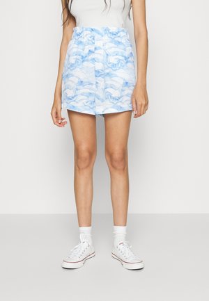 Bermudas azul claro com um padrão em aquarela, cintura elástica e bolsos laterais. Combinadas com sapatos e meias brancas.