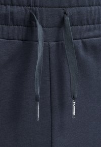 Pantalones de chándal azul marino con una tela texturizada, cinturilla elástica y cordones ajustables con puntas de plástico.